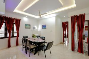 a dining room with red curtains and a table and chairs at Heaven Stay in Varkala
