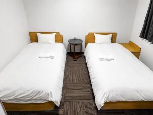 two beds sitting next to each other in a room at スマートホテル福島駅前店 in Fukushima