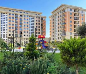 a playground in a park with two tall buildings at Huzur tapacaginiz ev in Sumqayıt