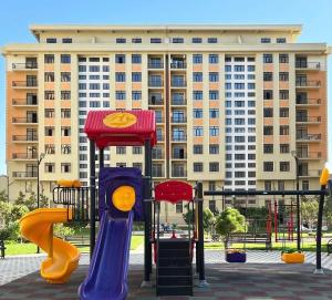 a playground in front of a large building at Huzur tapacaginiz ev in Sumqayıt