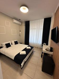 a bedroom with a bed and a desk and a television at Rulers Smart Rooms in Satu Mare