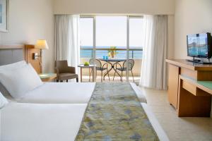 a hotel room with a bed and a view of the ocean at Atlantica Miramare Beach in Limassol
