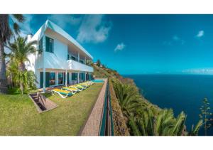 a house on top of a hill next to the ocean at Villa Amelia in Caniço