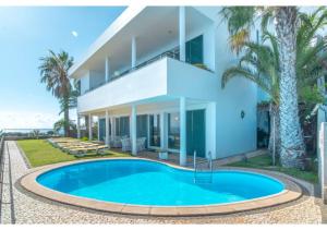 a villa with a swimming pool in front of a building at Villa Amelia in Caniço