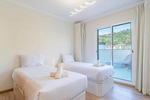 two beds in a white room with a window at Sunflower Apartment in Caniço +18 photos