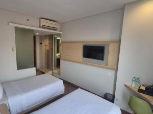a hotel room with two beds and a flat screen tv at Alltrue Lite Senen Jakarta in Jakarta