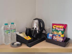a kitchen counter with a coffee maker and snacks and water at Alltrue Lite Senen Jakarta in Jakarta