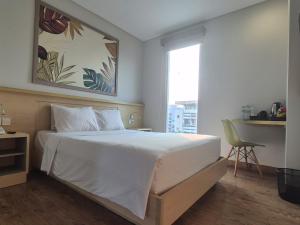 a bedroom with a large white bed and a window at Alltrue Lite Senen Jakarta in Jakarta