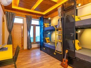a room with bunk beds and a desk and a guitar at The Hosteller Chakrata in Chakrāta