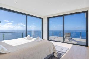 a bedroom with a bed and large glass windows at Celeste Villa in Ribeira Brava +30 photos