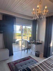 a bedroom with a bed and a desk and a chandelier at La Flamingo Guesthouse in Walvis Bay
