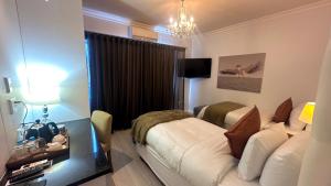 a bedroom with a bed and a desk and a chandelier at La Flamingo Guesthouse in Walvis Bay
