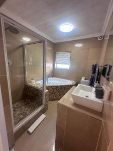 a bathroom with a tub and a sink and a shower at La Flamingo Guesthouse in Walvis Bay +76 photos