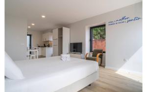 a white bedroom with a large bed and a kitchen at Jardim Mar Flats in Jardim do Mar
