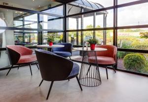 a group of chairs and tables in a room with windows at B&B HOTEL Reims Tinqueux in Reims
