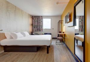 a hotel room with a large bed and a desk at B&B HOTEL Reims Tinqueux in Reims