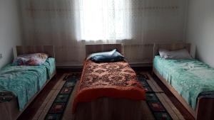 two beds sitting in a room with a window at House Ali in Klyuchi
