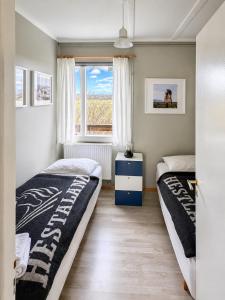 two beds in a room with a window at Hestaland Riverside Cottage in Staðarhús