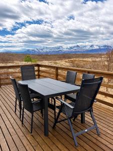 a black table and chairs on a deck with mountains at Hestaland Riverside Cottage in Staðarhús