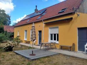 a yellow house with a table and an umbrella at La maison de Claudine in Bergues