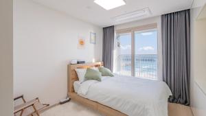 a bedroom with a bed and a large window at E7 YangYang Jukdo - Yangyang Stay Dongsan in Saetchak