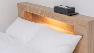 a bed with a wooden headboard with a black box on it at E7 YangYang Jukdo - Yangyang Stay Dongsan in Saetchak
