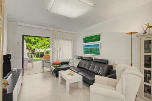 a living room with a black leather couch and chairs at Bungalow meloneras in San Bartolomé