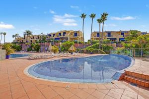 a large swimming pool with chairs and buildings in the background at Bungalow meloneras in San Bartolomé
