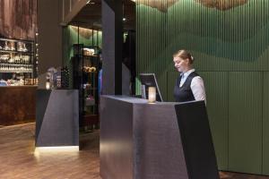 a woman standing behind a counter at a bar at Radisson Blu Polar Hotel, Spitsbergen in Longyearbyen