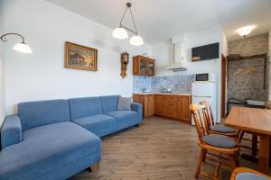 a living room with a blue couch and a kitchen at Apartments Hradný Mur in Bojnice