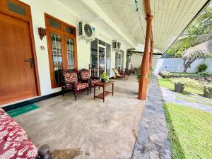 a porch of a house with chairs and a table at Devon Surf . Inn - Hiriketiya in Dickwella +91 photos