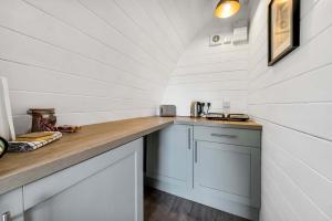 a kitchen with white cabinets and a wooden counter top at Dreish - Glamping Pod in Forfar +22 photos