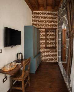 a room with a wooden table and a tv on a wall at Taş Avlu Konaklama Tesisi in Diyarbakır