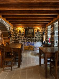 a dining room with wooden tables and a stone wall at Taş Avlu Konaklama Tesisi in Diyarbakır