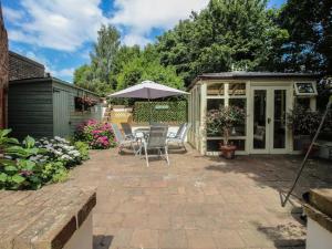 a patio with an umbrella and chairs and a greenhouse at Hadley Park Windmill in Telford