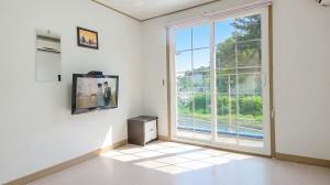 a white room with a large window and a tv at Samcheok Healingcamp Pension in Samcheok