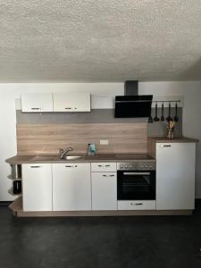 a kitchen with white cabinets and a sink at NEU! Moderne Ferienwohnung Knüllwald in Knüllwald