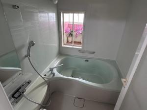 a bathroom with a tub with a window and pink flowers at 勝浦の家 in Katsuura