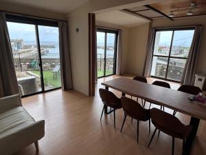 a dining room with a table and chairs and windows at 勝浦の家 in Katsuura