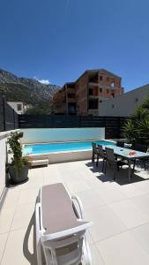 a patio with chairs and a table and a pool at Wind Rose Bura-beachfront in Igrane