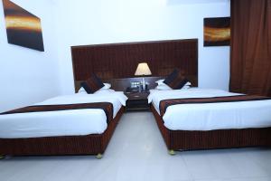 a hotel room with two beds and a lamp at Hotel Kohinoor, Bharuch in Bharūch