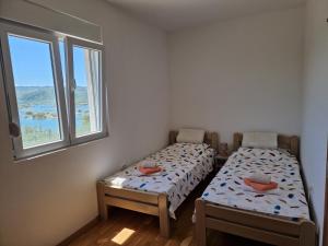 two beds in a room with two windows at Vuković house - Lake View & Nature in Kuside
