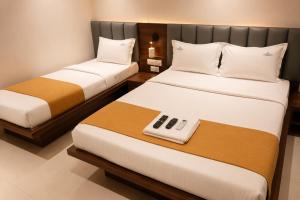 two beds in a hotel room with a remote control at SRS Jade Empire in Kammasandra