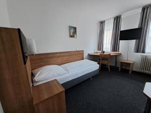 a bedroom with a bed and a desk and a table at Hotel zur Post in Weilheim an der Teck