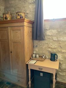 a wooden cabinet and a table in a room at Au bout du pré in Pézenas