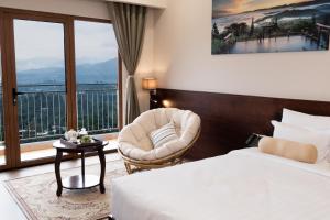 a hotel room with a bed and a chair and a window at Memories Hotel in Bảo Lộc +74 photos