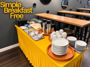 a yellow table with plates and cups on it at Smile Hotel Shah Alam ICity in Shah Alam