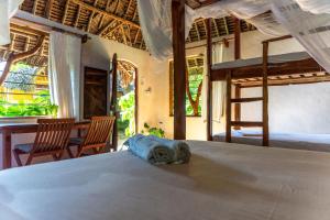 a bedroom with a bed and a table and chairs at Distant Relatives Ecolodge & Backpackers in Kilifi +139 photos