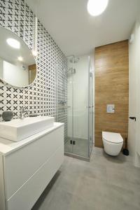 a bathroom with a toilet and a sink and a shower at A very cozy apartment with a large bed in Wrocław +10 photos