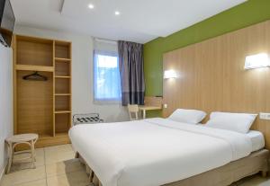 a bedroom with a large white bed and a window at B&B HOTEL Nîmes Ville Active 3 étoiles in Nîmes